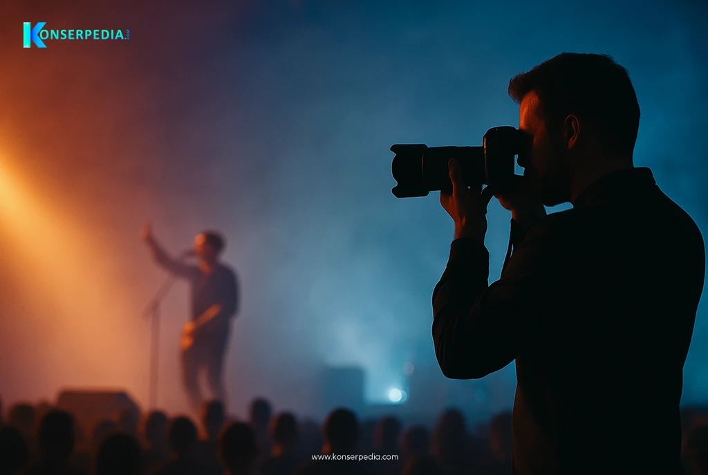 Seorang fotografer konser sedang memotret musisi dengan cahaya dramatis, menggambarkan cara menjadi fotografer konser.